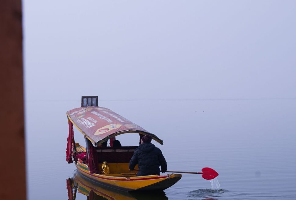 A scenic view of a traditional shikara boat on Dal Lake in Srinagar, Kashmir.