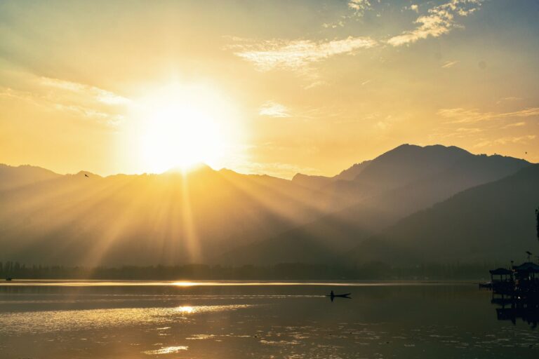 Golden sunrise illuminating the hills over Dal Lake in Srinagar, creating a tranquil natural scene.
