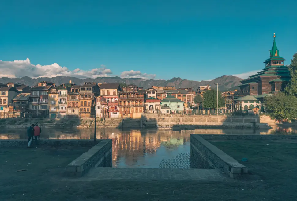 Scenic view of buildings by the Jhelum River in Srinagar, Kashmir with a mosque in the backdrop.